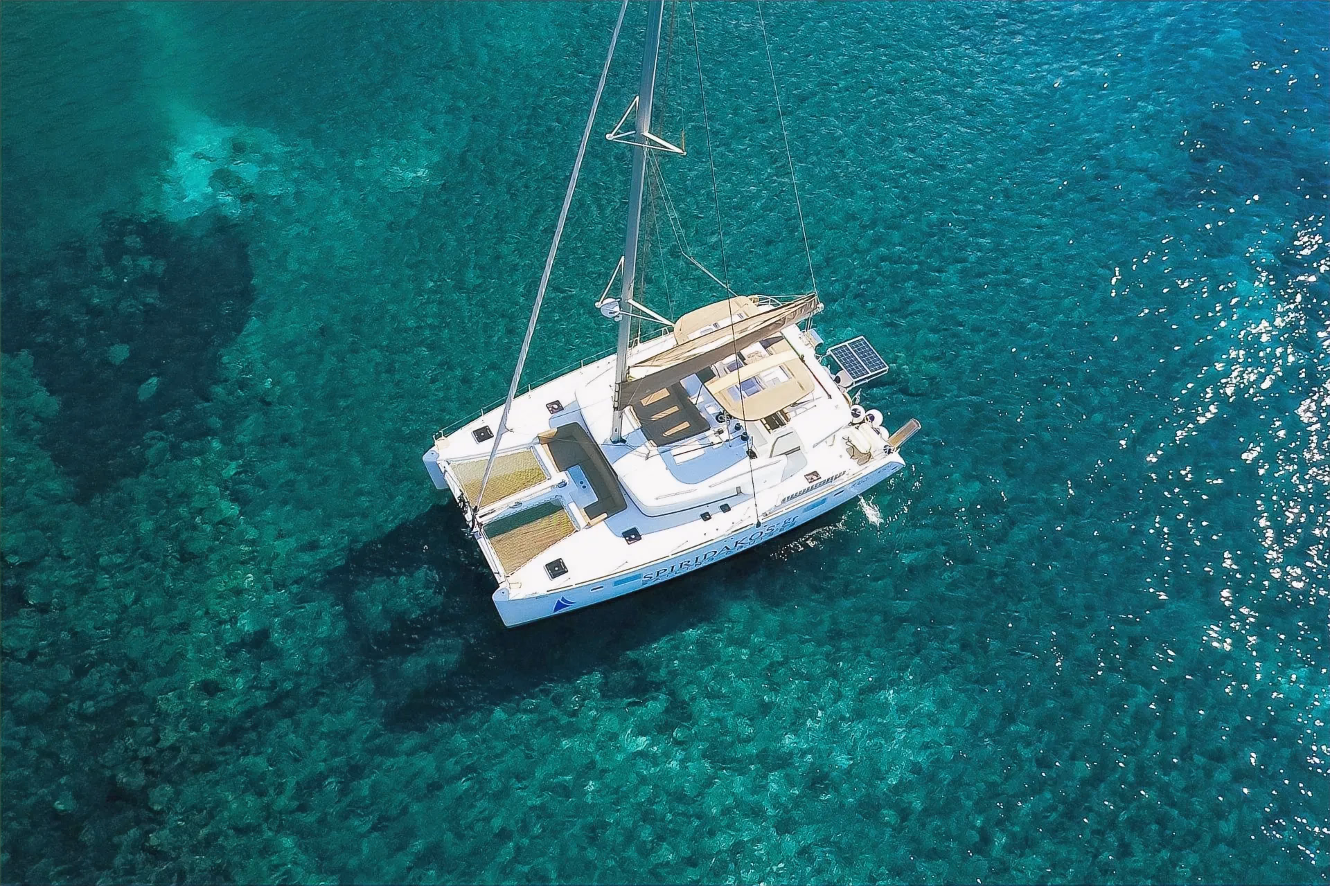 Катамаран на якоре в прозрачной бирюзовой воде у Санторини, вид сверху